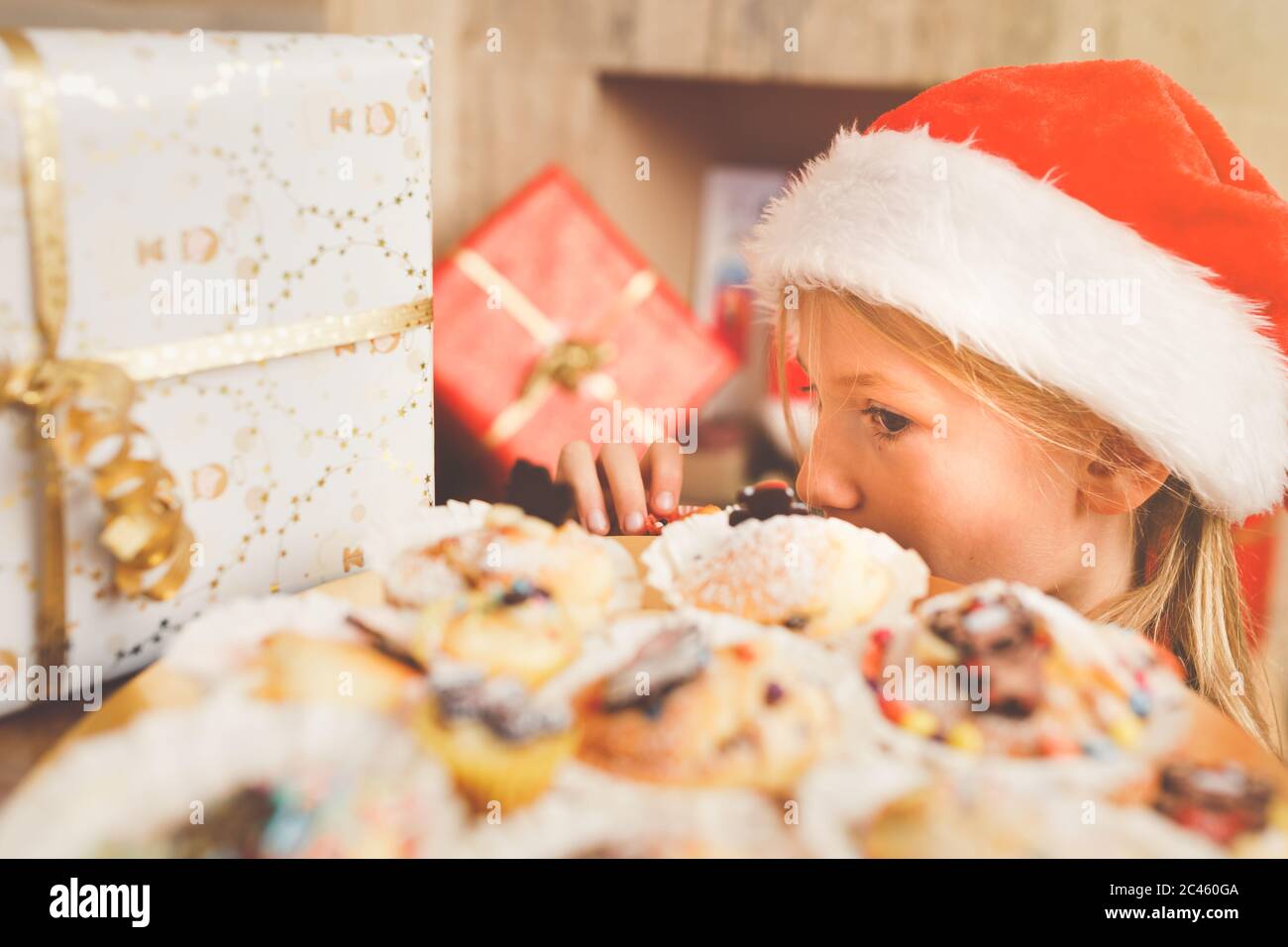 Jeune fille, âge primaire, regardant à l'assiette pleine de grands muffins colorés Banque D'Images