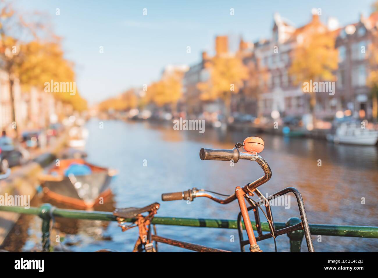Vélo avec cloche orange devant le canal à Amsterdam en automne Banque D'Images