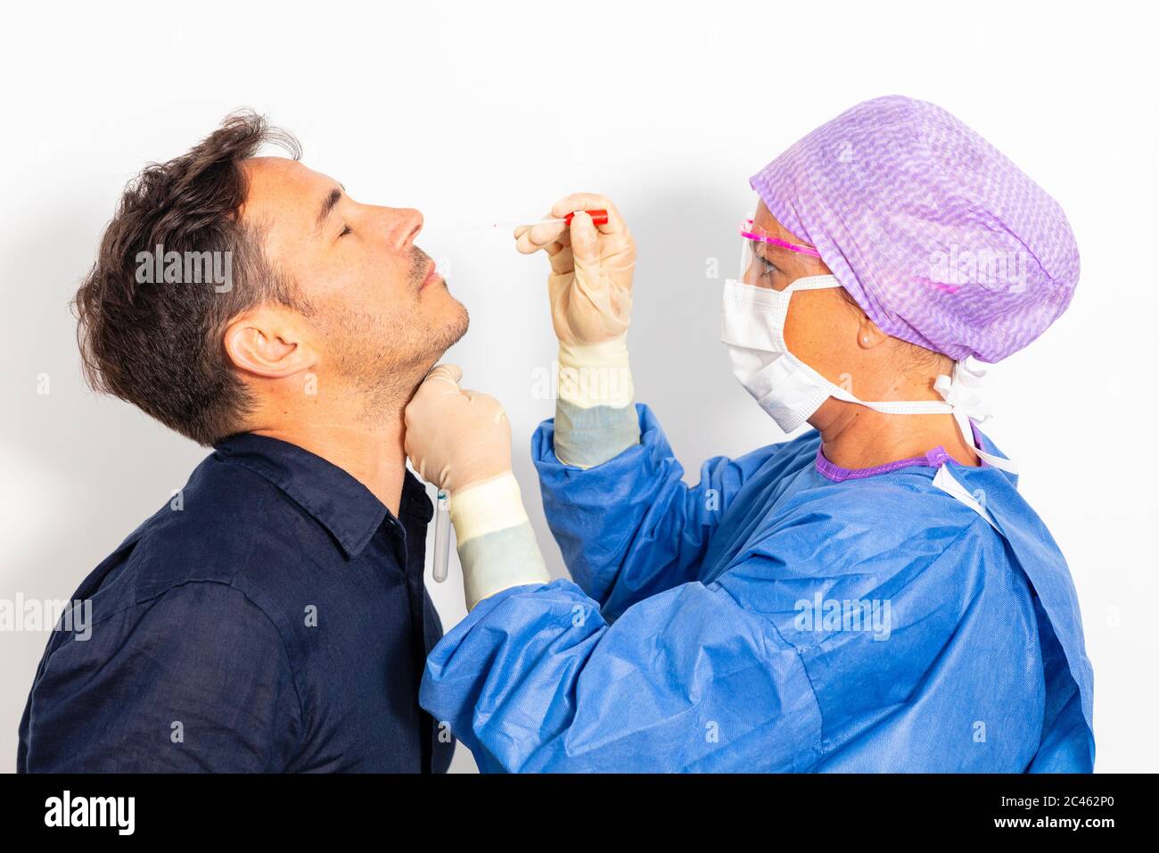 Un médecin en costume protecteur prenant un écouvillon nasal d'une personne pour tester une éventuelle infection à coronavirus Banque D'Images