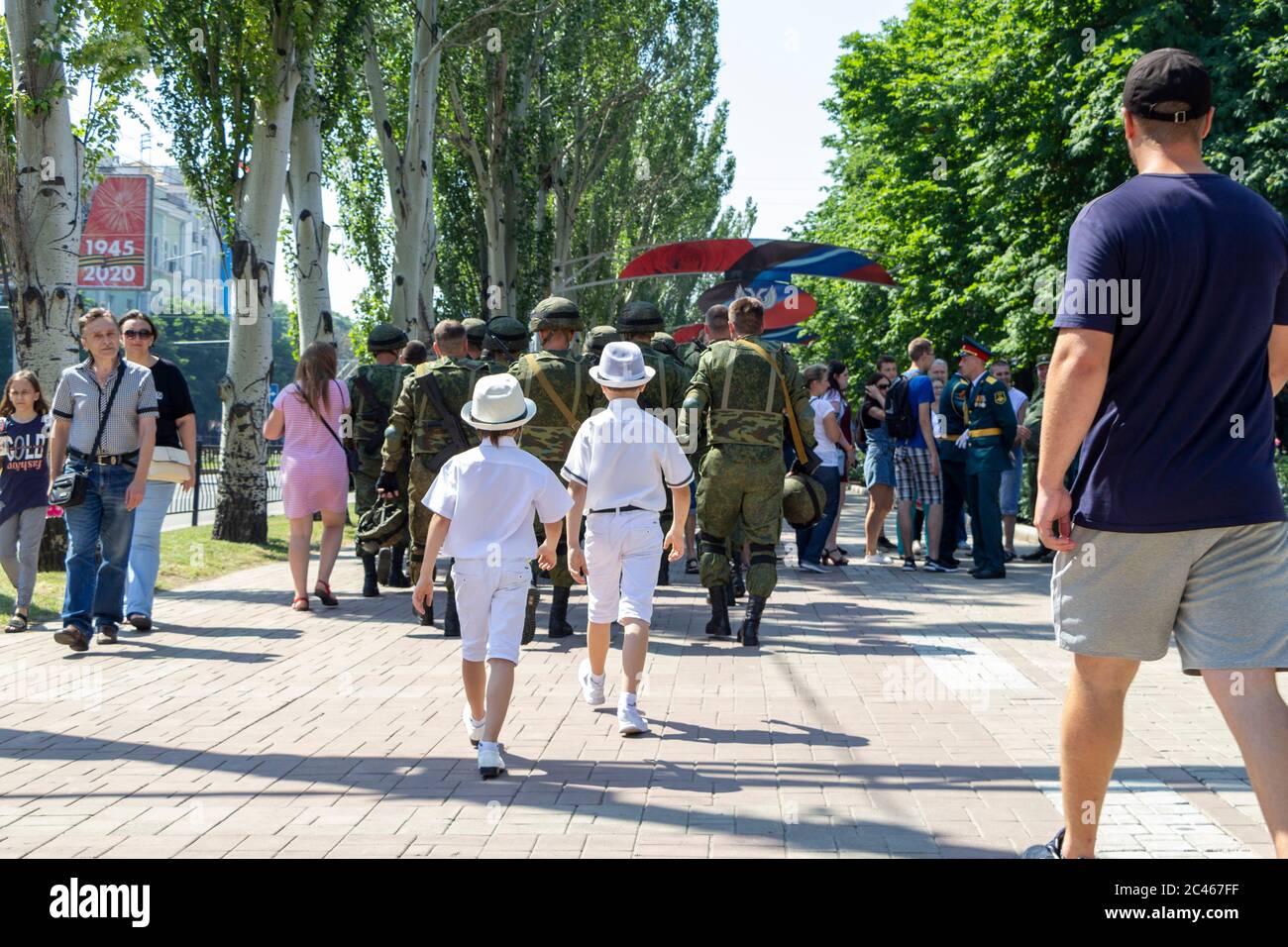 Donetsk, Donetsk People Republic, Ukraine - 24 juin 2020 : deux garçons en vêtements et chapeaux de fête blancs vont après l'armée après le para du jour de la victoire Banque D'Images
