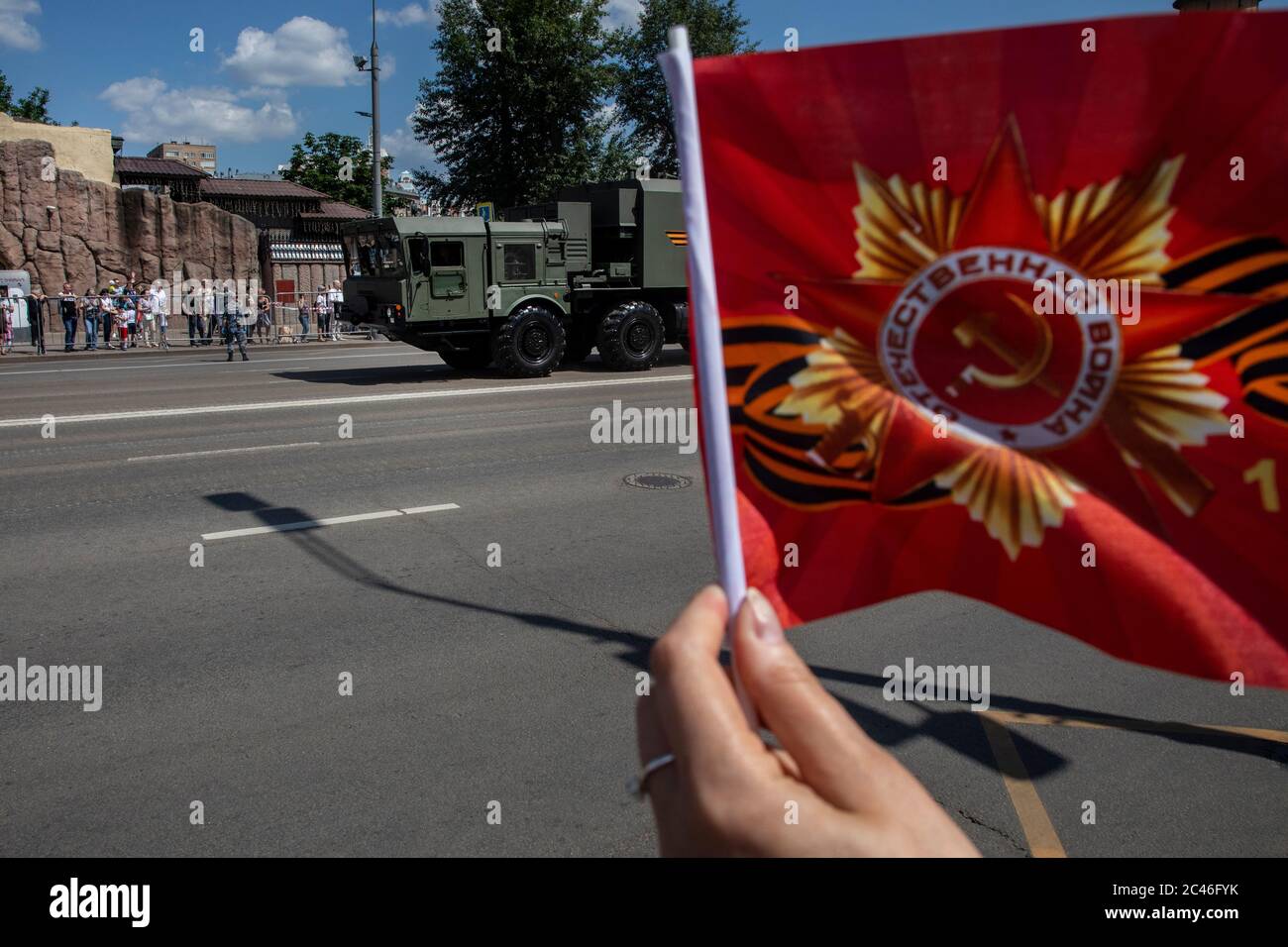 Moscou, Russie. 24 juin 2020 UNE femme agitant des drapeaux rouges rencontre des véhicules militaires venant du défilé militaire du jour de la victoire sur la place Rouge marquant le 75e anniversaire de la victoire pendant la Seconde Guerre mondiale Les défilés du jour de la victoire à travers la Russie ont été reportés du 9 mai au 24 juin en raison des restrictions imposées pour empêcher la propagation du nouveau coronavirus Banque D'Images