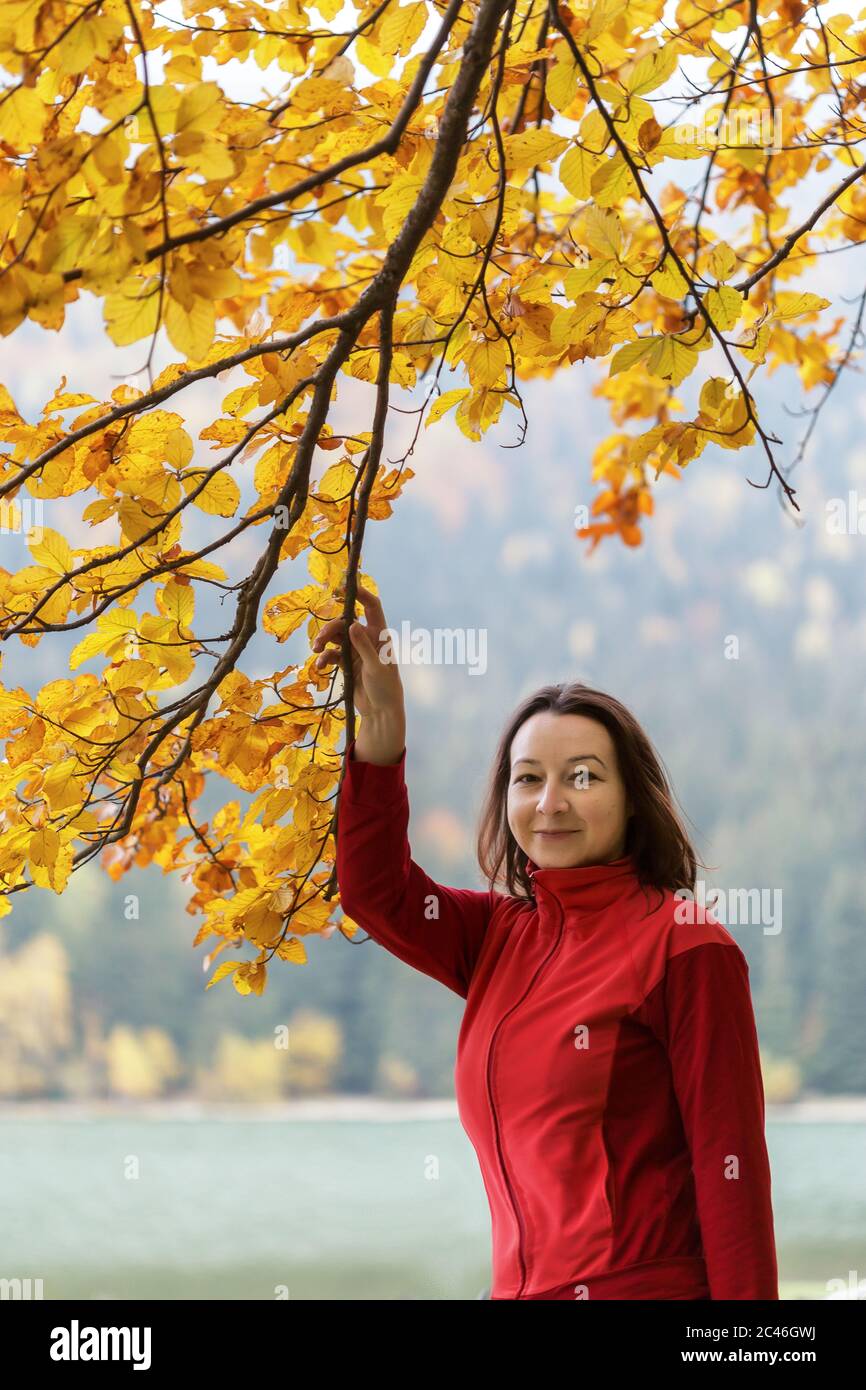 Femme vêtue à la manière décontractée près des branches d'un arbre d'automne Banque D'Images
