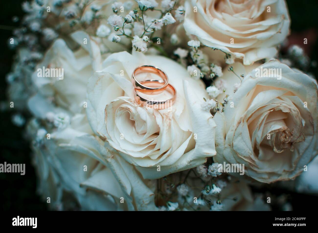 Anneaux de mariage dorés couchés sur le bouquet blanc de fleurs Banque D'Images