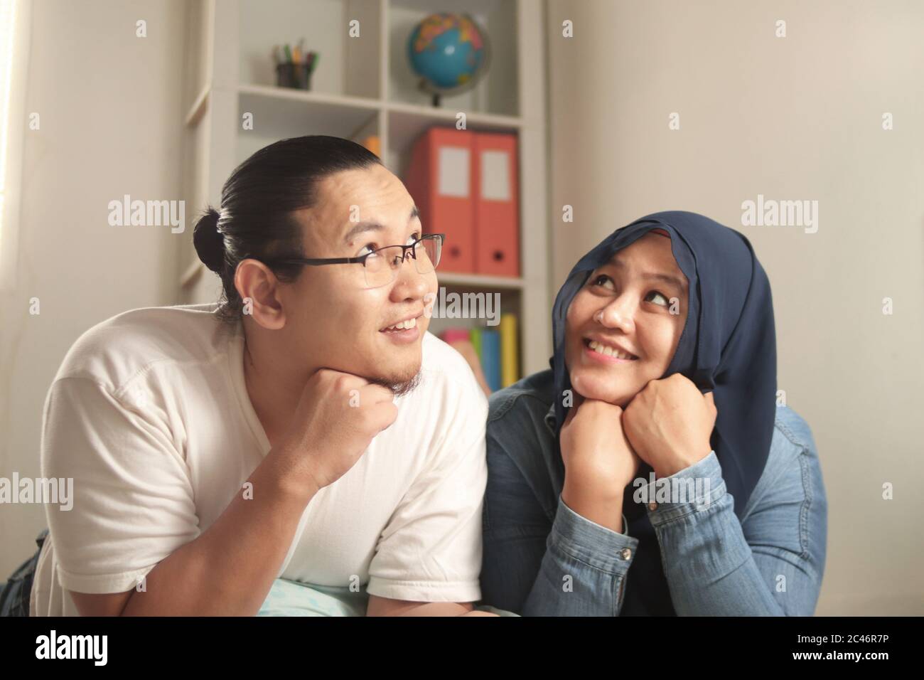 Jeune couple musulman asiatique se détendant dans leur nouvelle maison, regardant penser et sourire, imaginant rêver de leur avenir, mari femme planifiant la vie conceep Banque D'Images