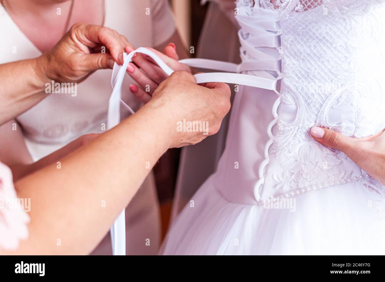 les demoiselles d'honneur enfilent la robe de la mariée Banque D'Images