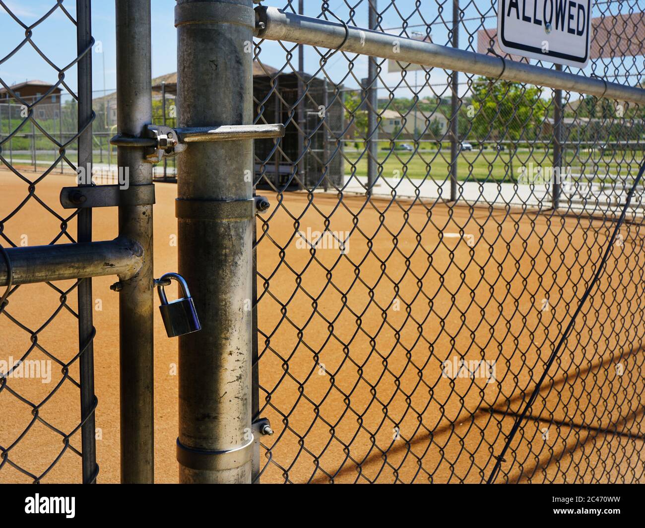 Baseball Diamond à travers une porte à maillons de chaîne verrouillée. Banque D'Images