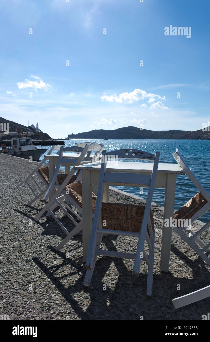 Des tables et des chaises de taverne traditionnelles sont disponibles au port de l'île grecque d'iOS. Vue sur la magnifique baie du port. Copier l'espace. Banque D'Images