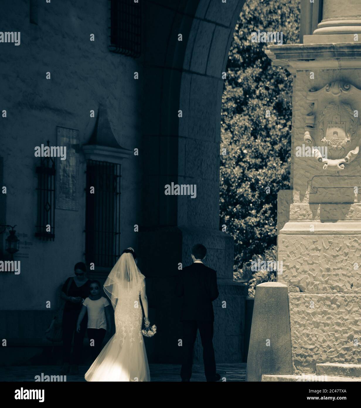 Vue arrière de la mariée et du marié qui se promeunaient dans l'arcade pillée vers la cour et les jardins en contrebas du palais de justice du comté de Santa Barbara, CA Banque D'Images