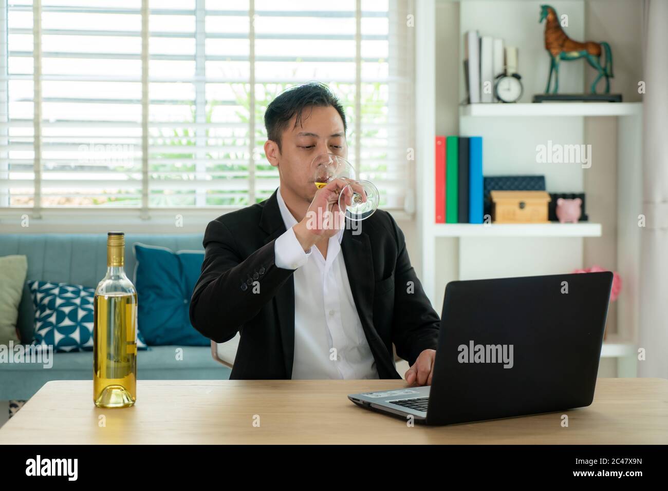 Un homme asiatique virtuel happy hour et boire du vin de raisin blanc en ligne avec son ami dans la vidéo conférence avec une tablette numérique pour un Banque D'Images