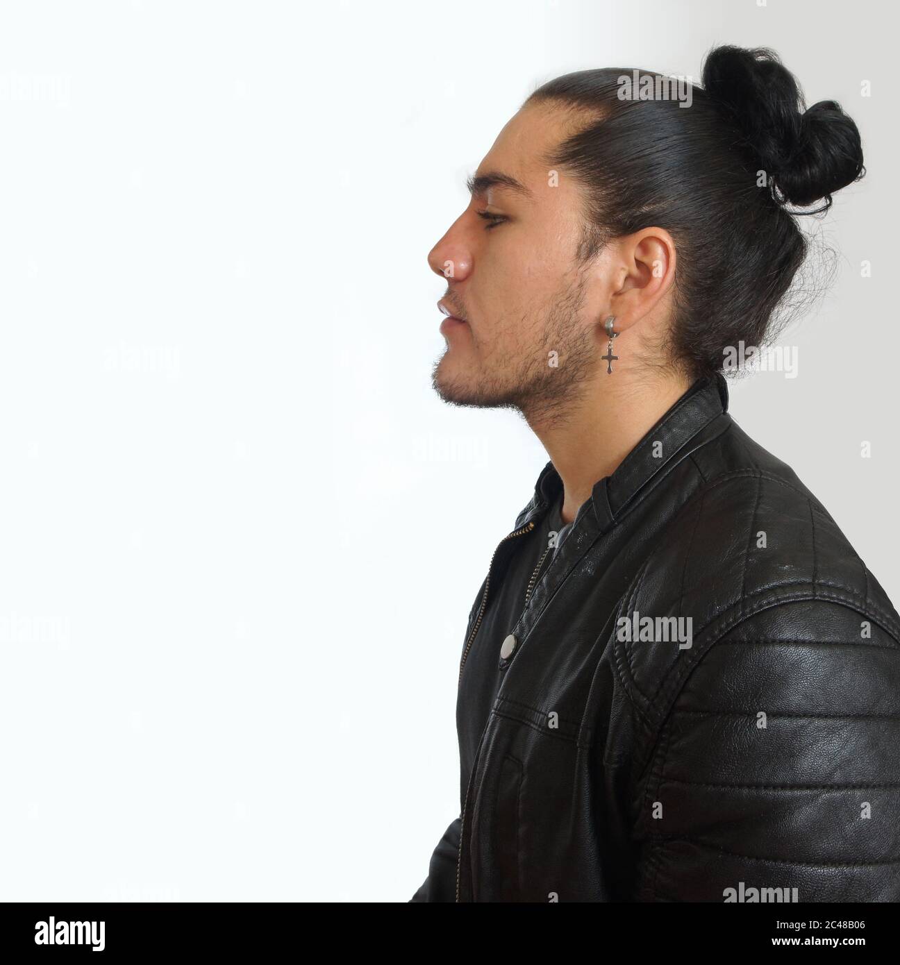Jeune hispanique avec les cheveux froncés fait noeud dans la robe noire et veste en cuir noir, vu dans le profil sur fond blanc Banque D'Images