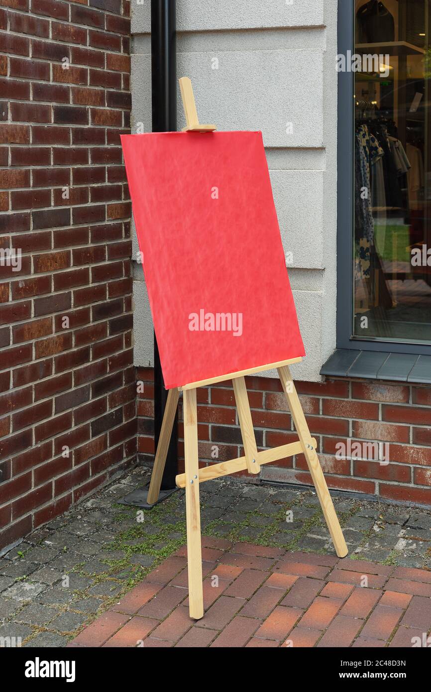 Easel artiste en bois avec maquette rouge vierge pour votre conception devant le mur en brique Banque D'Images