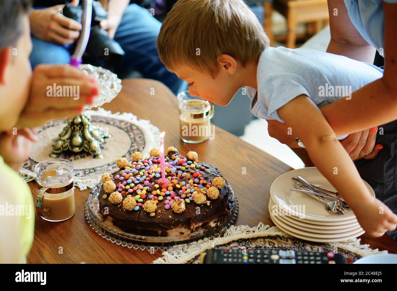 VAALS, PAYS-BAS - 16 août 2019 : un jeune garçon de deux ans soufflait une bougie sur un gâteau d'anniversaire au chocolat dans une maison. Banque D'Images