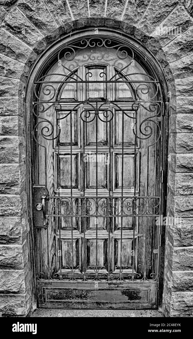 Prise de vue verticale en niveaux de gris d'une porte de style gothique fermée avec une clôture métallique Banque D'Images