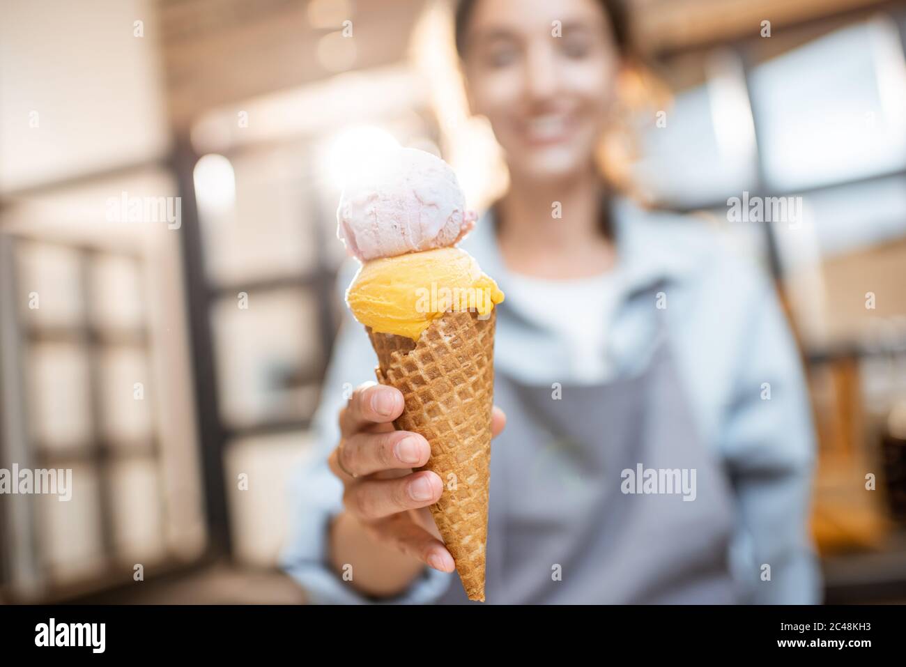 Une femme joyeuse vendait de la glace délicieuse dans un cornet de gaufres à l'intérieur, vendant des bonbons dans la boutique Banque D'Images