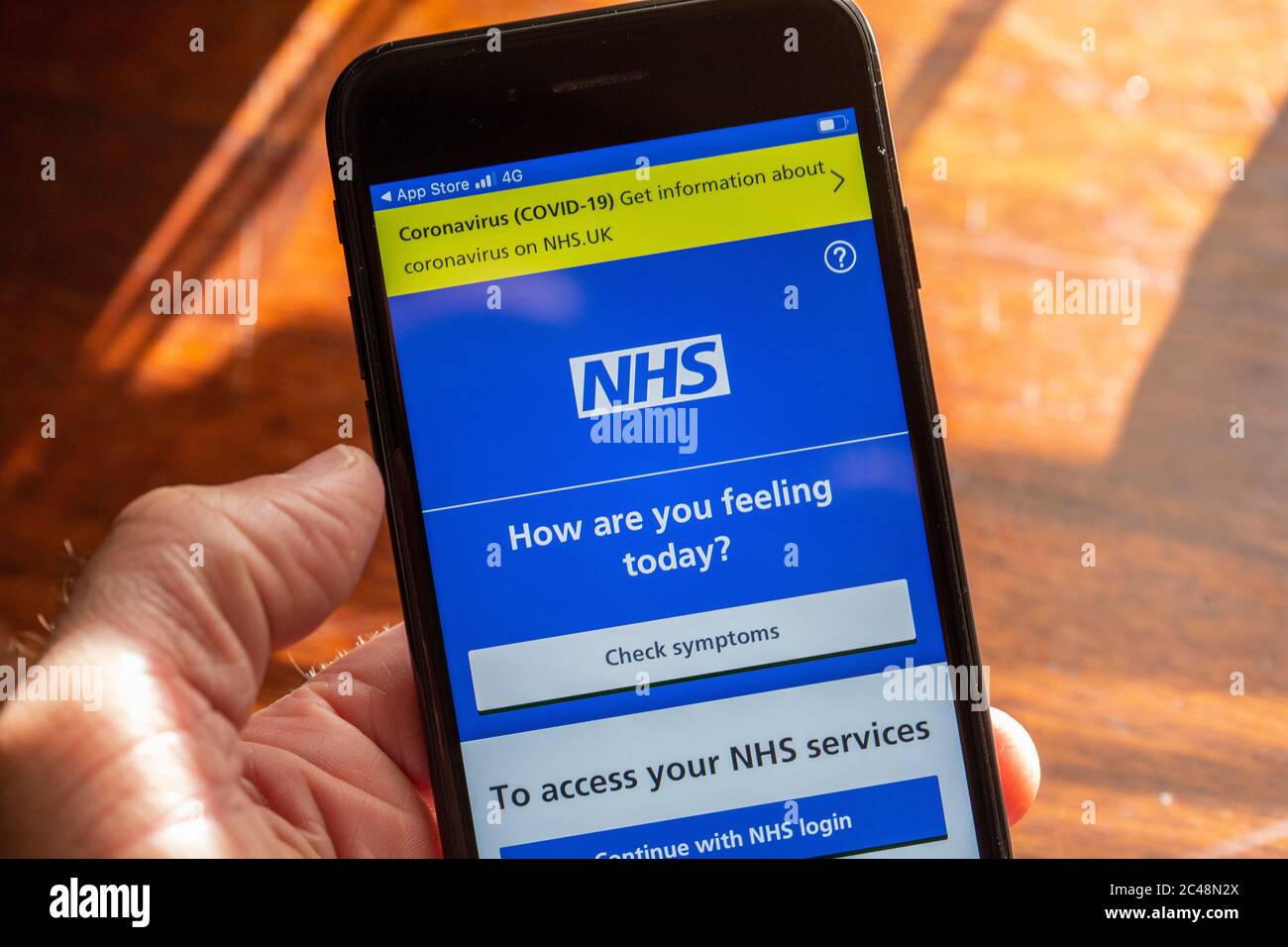 Main tenant un téléphone portable noir montrant l'application NHS Photo de Sam Mellish Banque D'Images