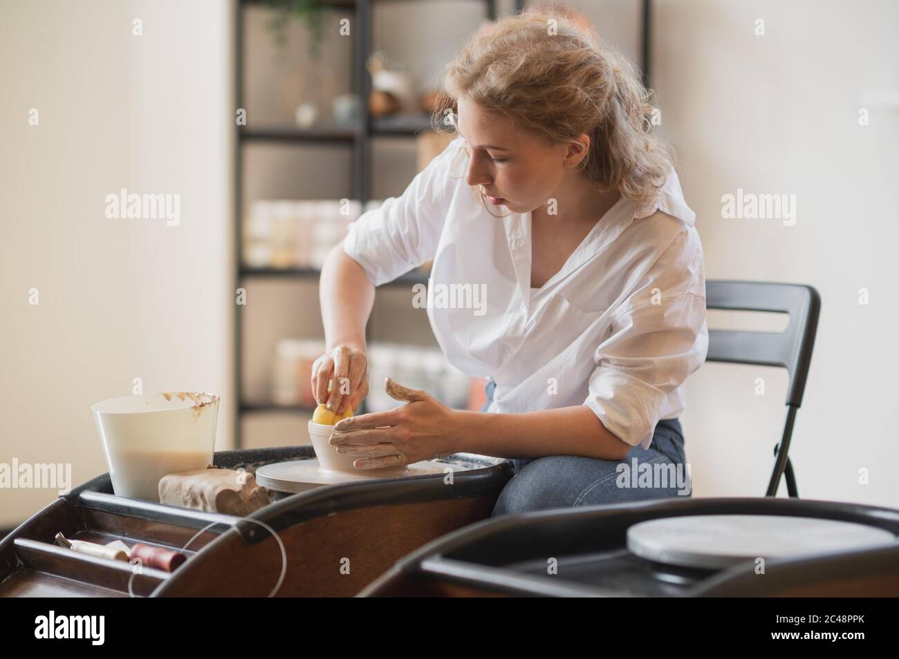 Femme travaillant sur la roue de potiers faisant des plats avec leurs propres mains. Photo en gros plan de l'argile de moulage sale mains Banque D'Images