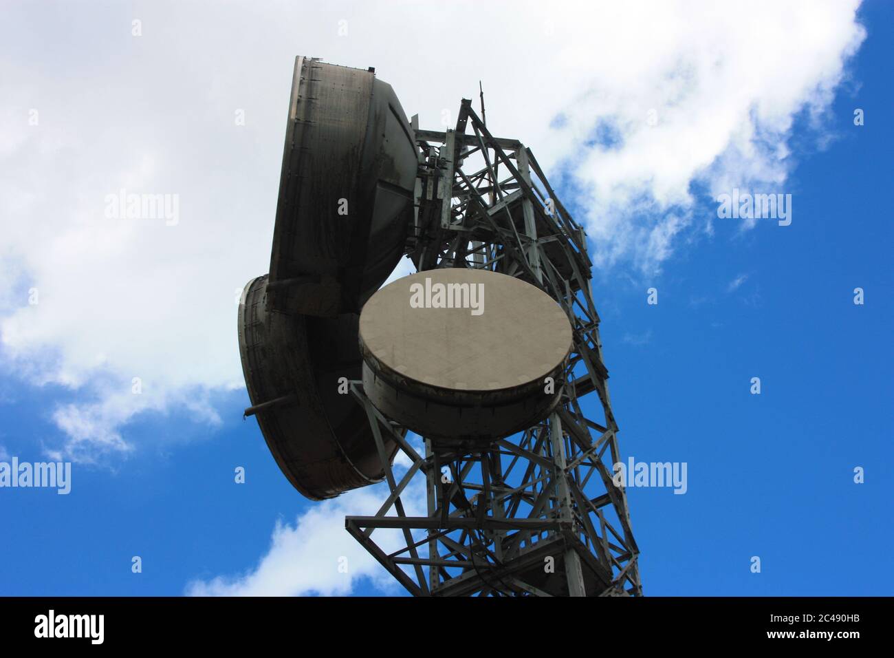 grandes antennes de grande taille transmettant des signaux avec les antennes paraboliques actuelles et les câbles électriques haute intensité et ciel bleu avec des nuages Banque D'Images