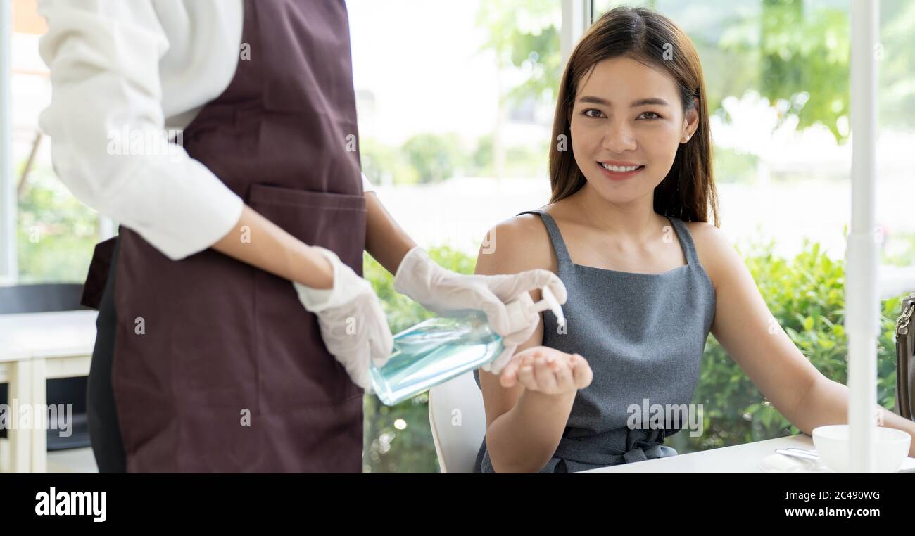 Panorama de la serveuse pousser gel alcool désinfectant pour les mains pour le client à la table de salle à manger pour le nettoyage des mains d'hygiène réduire l'infection du coronavirus covid-19 p. Banque D'Images