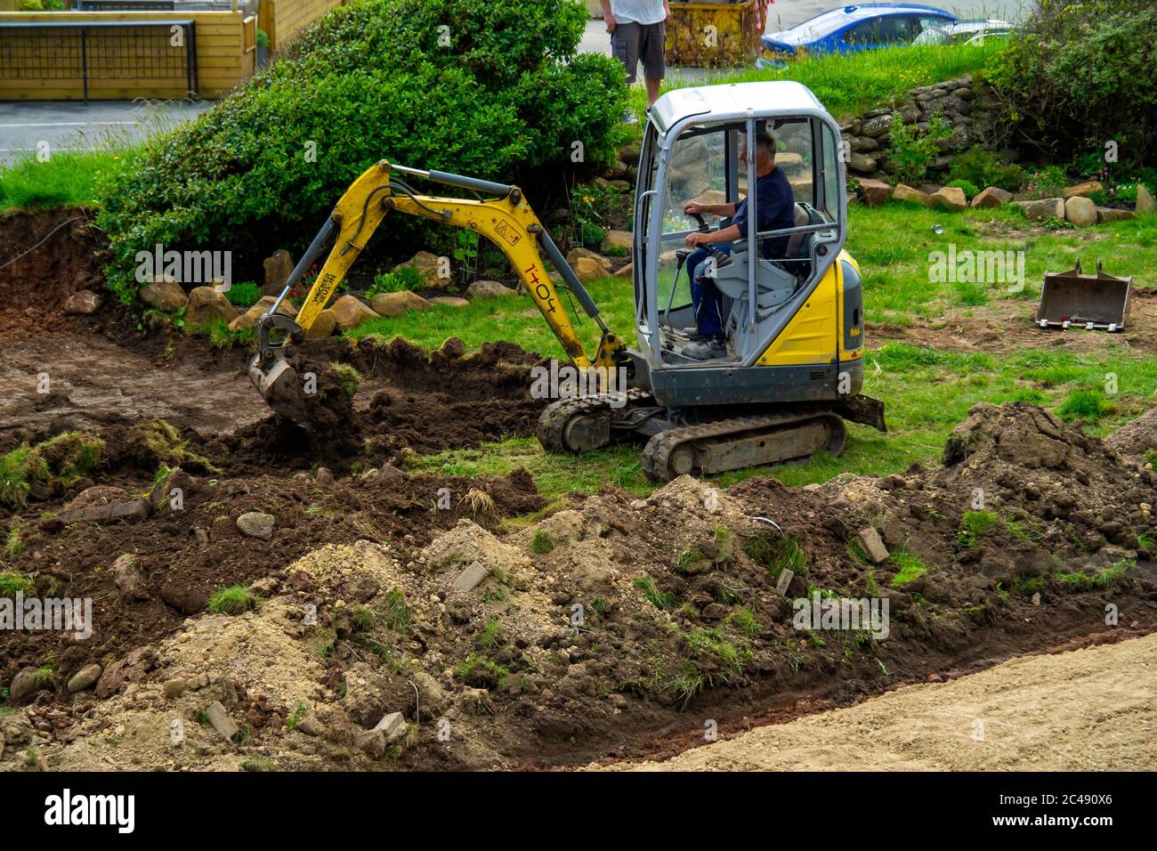 Une mini-pelle hydraulique servant à préparer un jardin pour l'aménagement paysager Banque D'Images