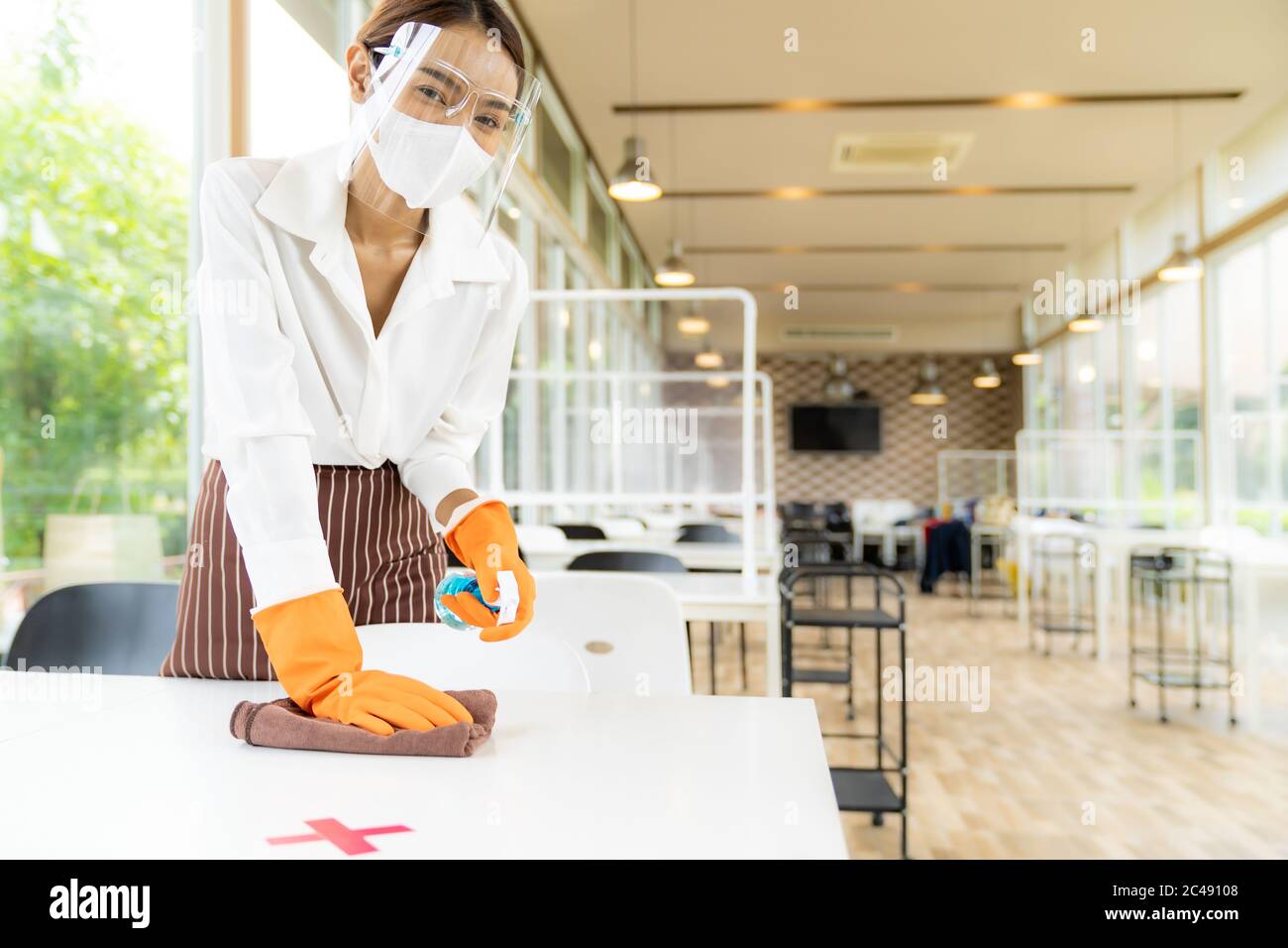 Portrait attrayant asiatique serveuse porter masque et écran facial table de nettoyage avec de l'alcool et de l'essuie-glace avant d'accueillir le client. Nouvelle hygiène normale Banque D'Images