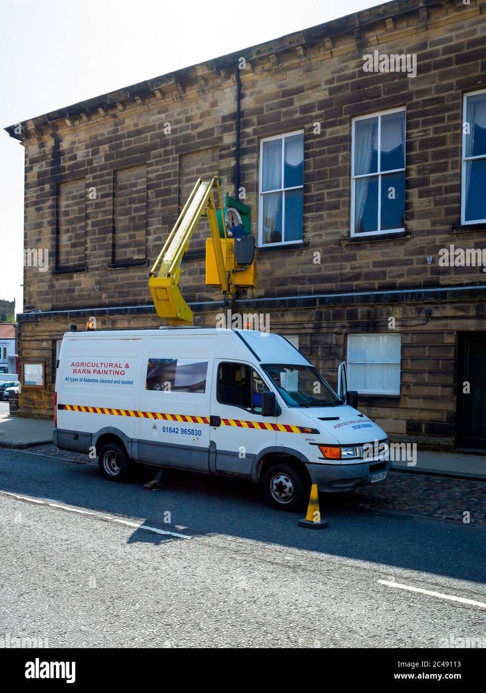 Homme sur un palan hydraulique effectuant une réparation de l'horloge sur la mairie de Stokesley North Yorkshire Banque D'Images