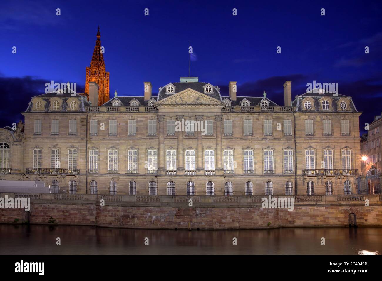Façade du Palais Rohan à Strasbourg, France, de nuit. La tour de la cathédrale notre-Dame donne sur le bâtiment. Banque D'Images