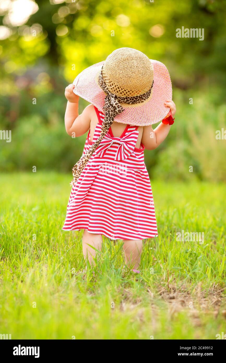 Petite fille en robe d'été et grand chapeau de paille se tient avec son  dos, espace pour le texte Photo Stock - Alamy