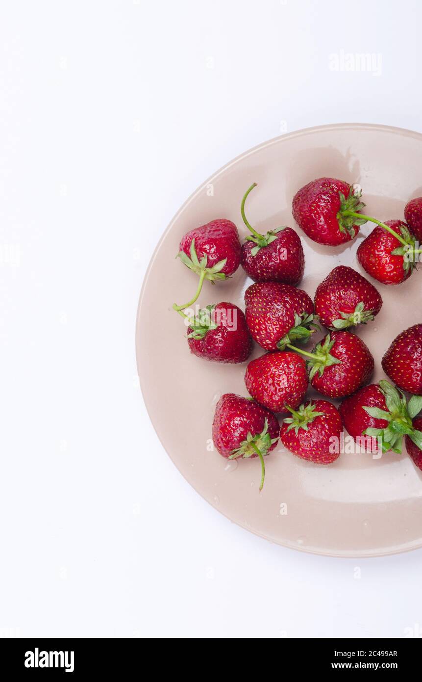 fraises rouges fraîches sur plaque pastel sur fond blanc Banque D'Images