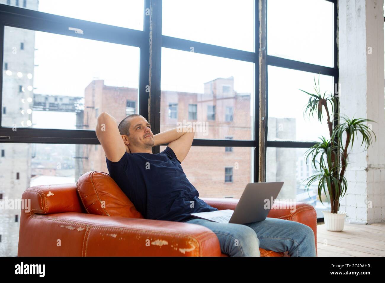 Homme adulte se relaxant à la maison avec un ordinateur portable à genoux Banque D'Images