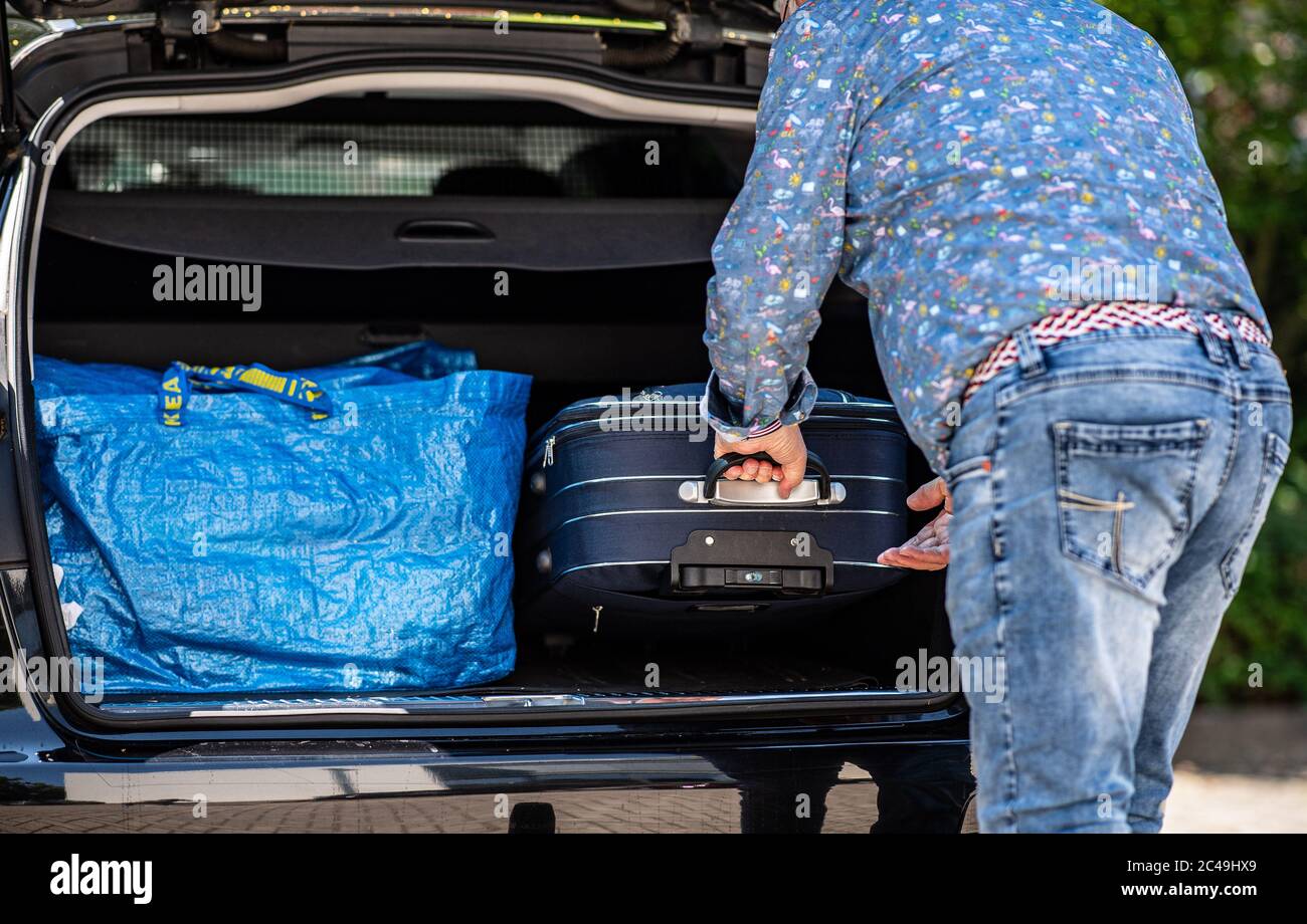 25 juin 2020, Rhénanie-du-Nord-Westphalie, Warendorf: Dieter Gretzke de Warendorf pousse ses valises dans le coffre de son véhicule. Avec sa femme, le couple retraité a dû retourner de Hambourg le 24.06.2020 sur leur chemin vers le nord quand ils ont reçu un appel téléphonique. Dans cet appel téléphonique, ils ont été informés qu'ils n'étaient pas autorisés à se rendre à leur camping sans un test de corona négatif. Le couple est donc revenu dans le quartier de Warendorf pour faire un frottis de corona le matin dans un centre mobile de test de corona à Oelde. Ils espèrent maintenant que le test est négatif et qu'ils pourront commencer leur vie Banque D'Images