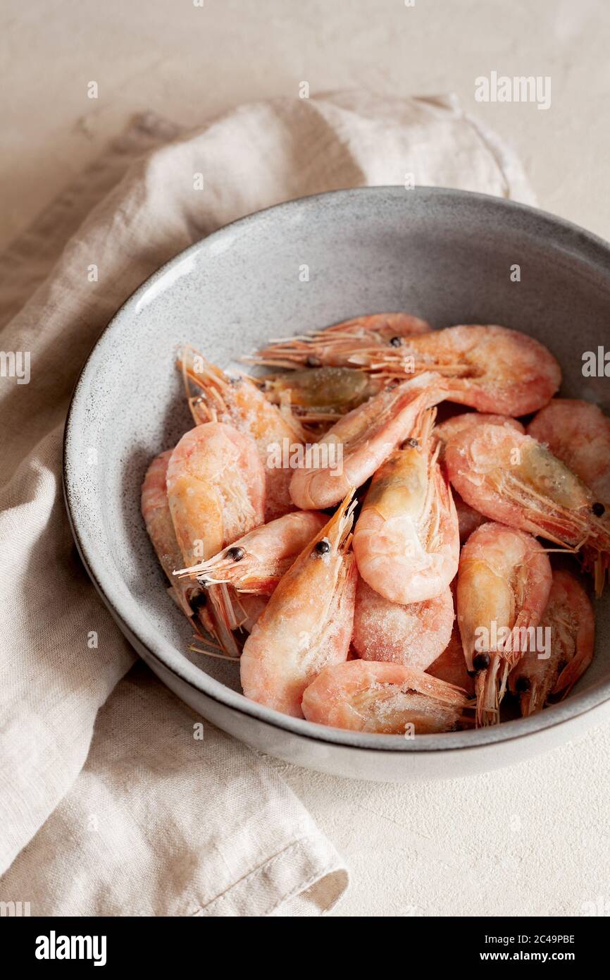 Crevettes surgelées sur une plaque grise en gros plan.ingrédient naturel de fruits de mer pour la cuisson.orientation verticale Banque D'Images