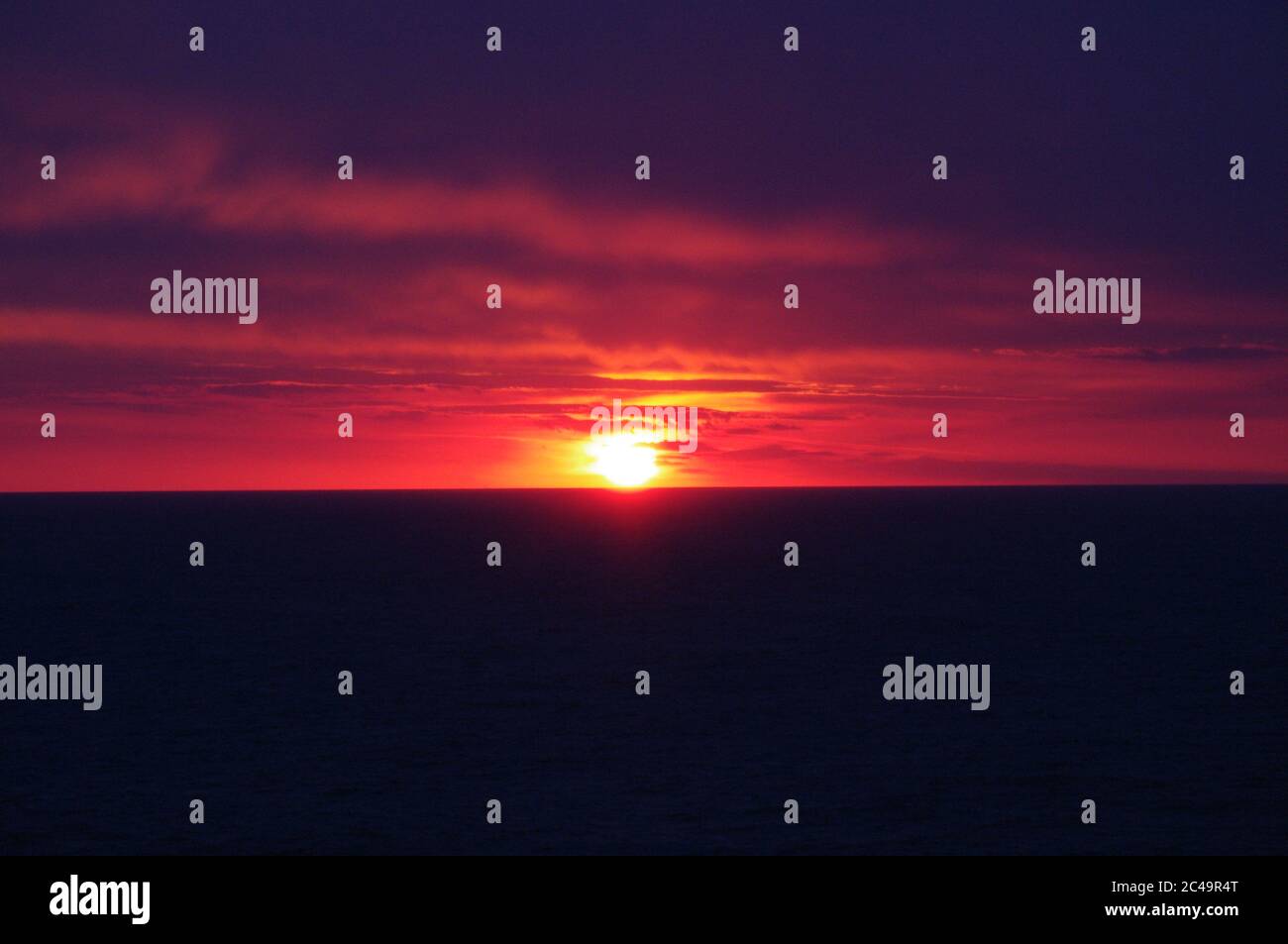 Séquence d'images d'un coucher de soleil, coucher de soleil rouge vif sur mer sombre avec nuages sombres Banque D'Images