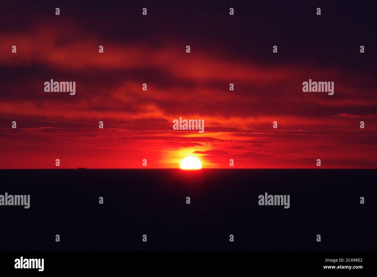 Séquence d'images d'un coucher de soleil, coucher de soleil rouge vif sur mer sombre avec nuages sombres Banque D'Images