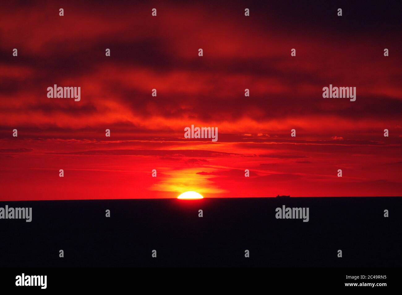 Séquence d'images d'un coucher de soleil, coucher de soleil rouge vif sur mer sombre avec nuages sombres Banque D'Images