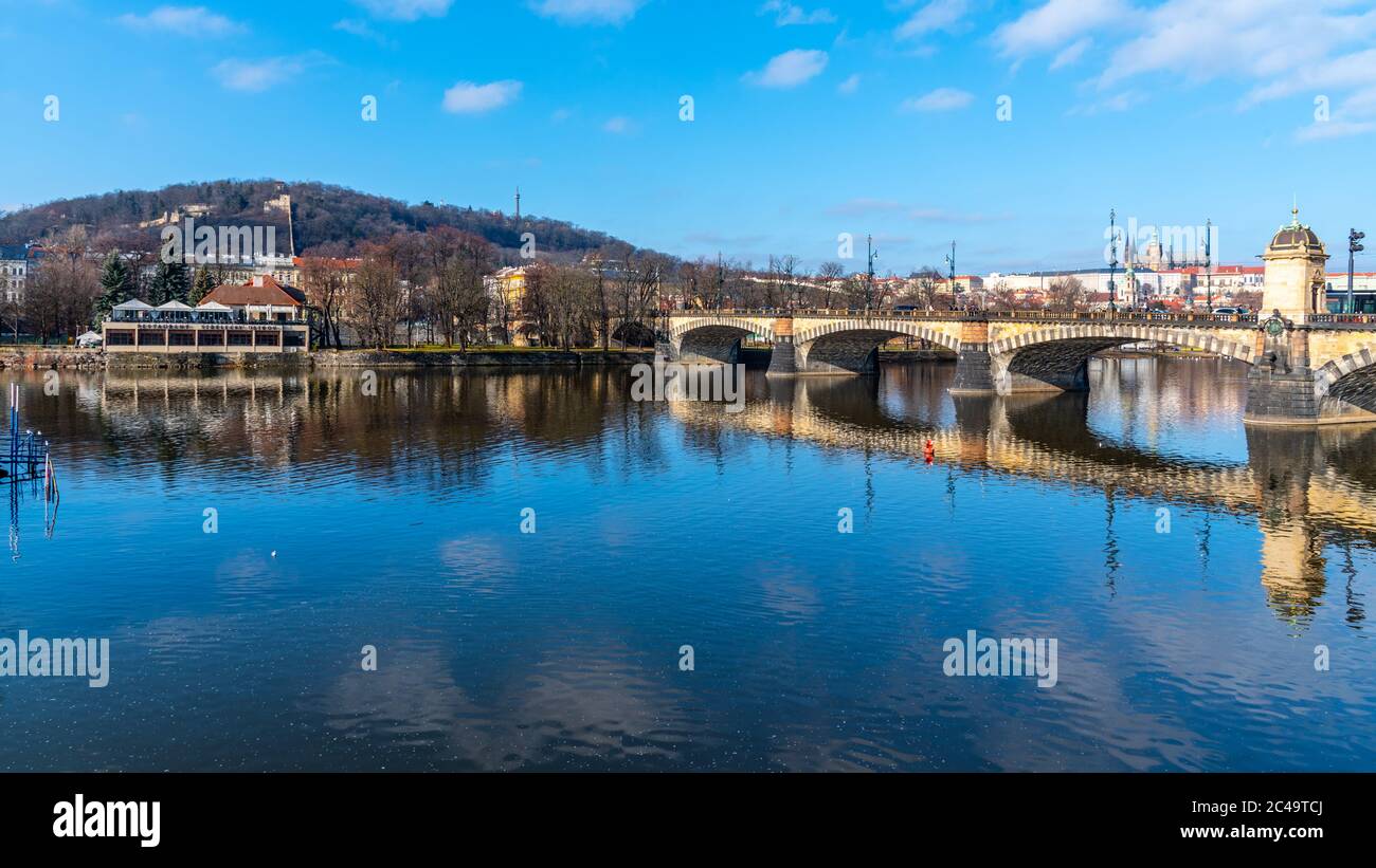 Pont de la légion, tchèque : la plupart des légion, se reflète dans la Vltava avec le château de Prague et la colline Petrin en arrière-plan. Journée d'hiver claire et ensoleillée à Prague, République tchèque. Banque D'Images