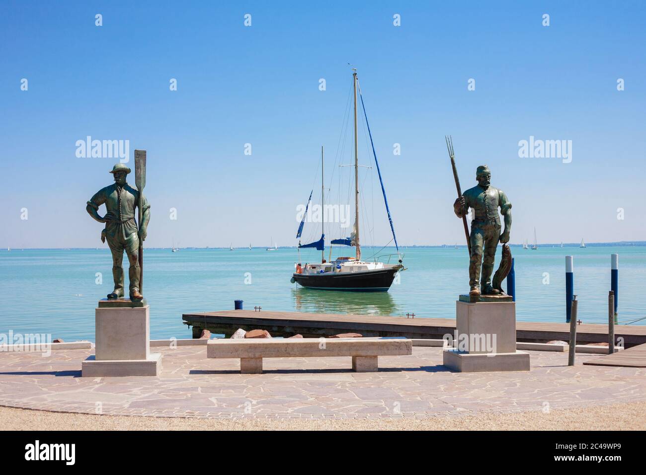 BALATONFURED, HONGRIE - 03 AOÛT 2013 : statues de pêcheur et d'homme en aviron à la plage de Balatonfured avec un voilier à l'arrière-plan sur le lac Balat Banque D'Images