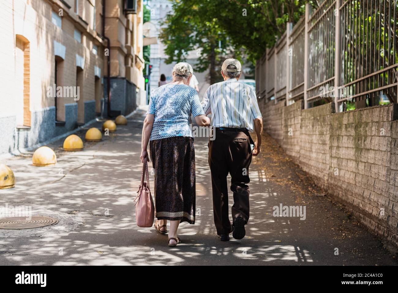 Couple senior marchant bras dans bras le long de la rue. Vue arrière. Concept de soutien mutuel dans la vieillesse Banque D'Images