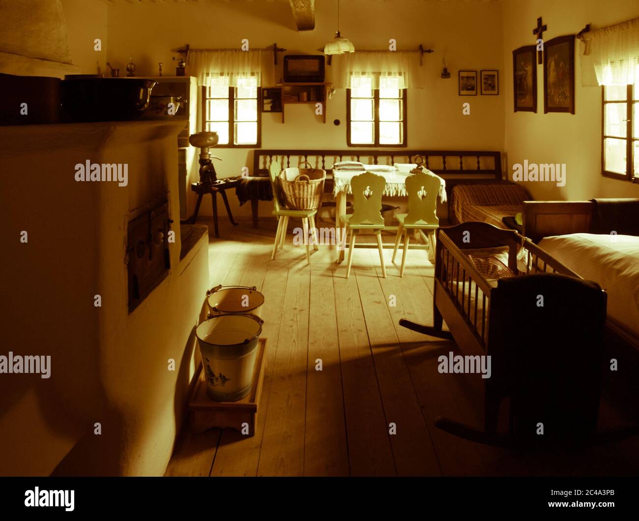 Chambre vintage avec lit, berceau, four, table et chaises dans la maison rurale ancienne. Image de style sépia. Banque D'Images