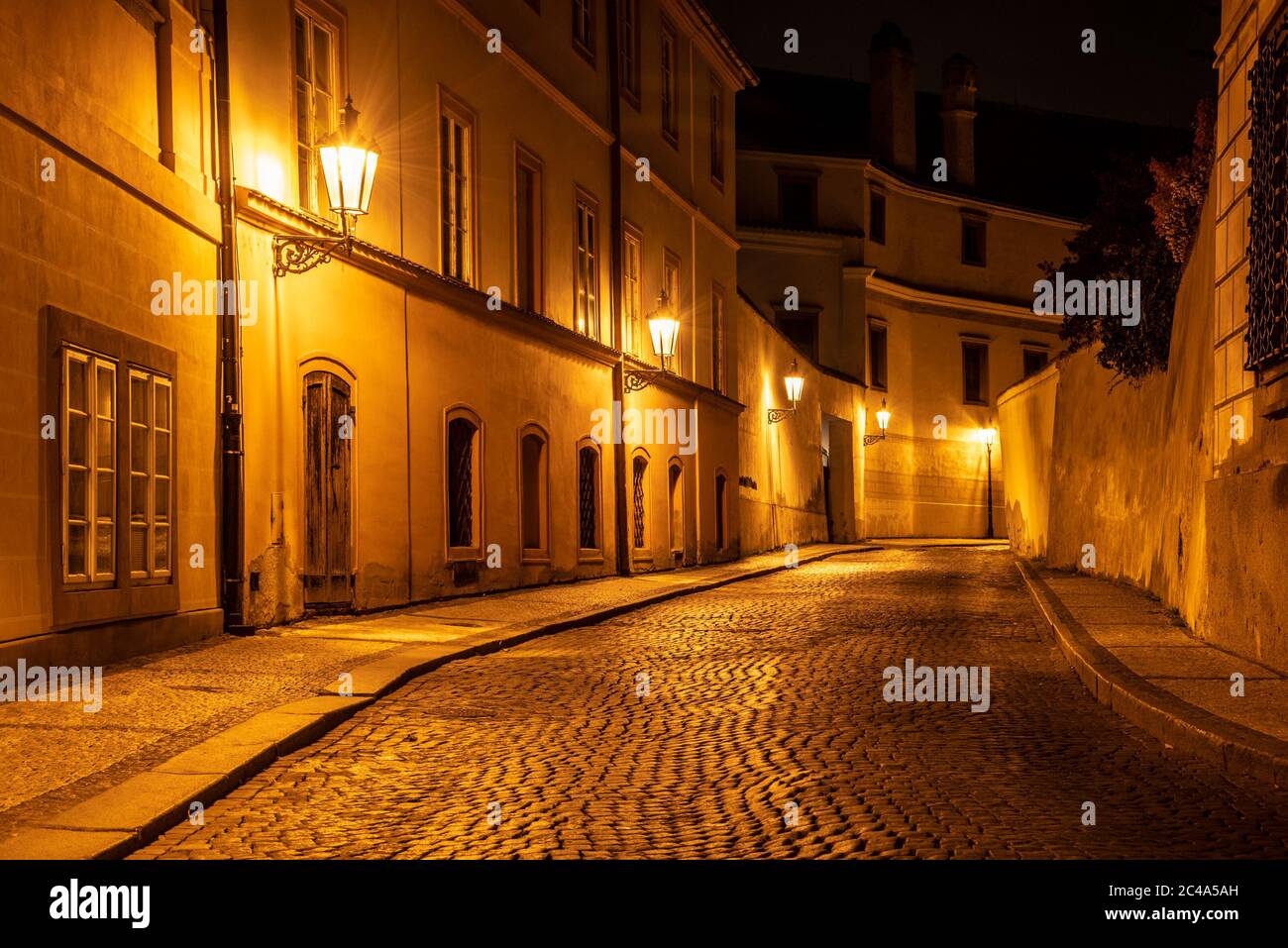 Petite rue pavée dans la vieille ville médiévale avec maisons illuminées par des lampes de rue d'époque, Novy svet, Prague, République tchèque. Prise de vue de nuit. Banque D'Images