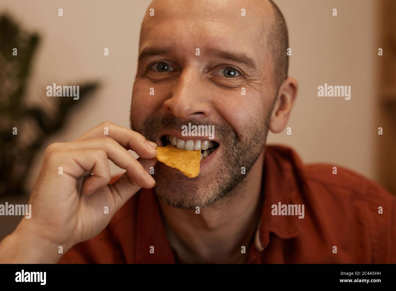 Portrait d'un homme mûr et en train de manger des frites et de sourire à l'appareil photo Banque D'Images