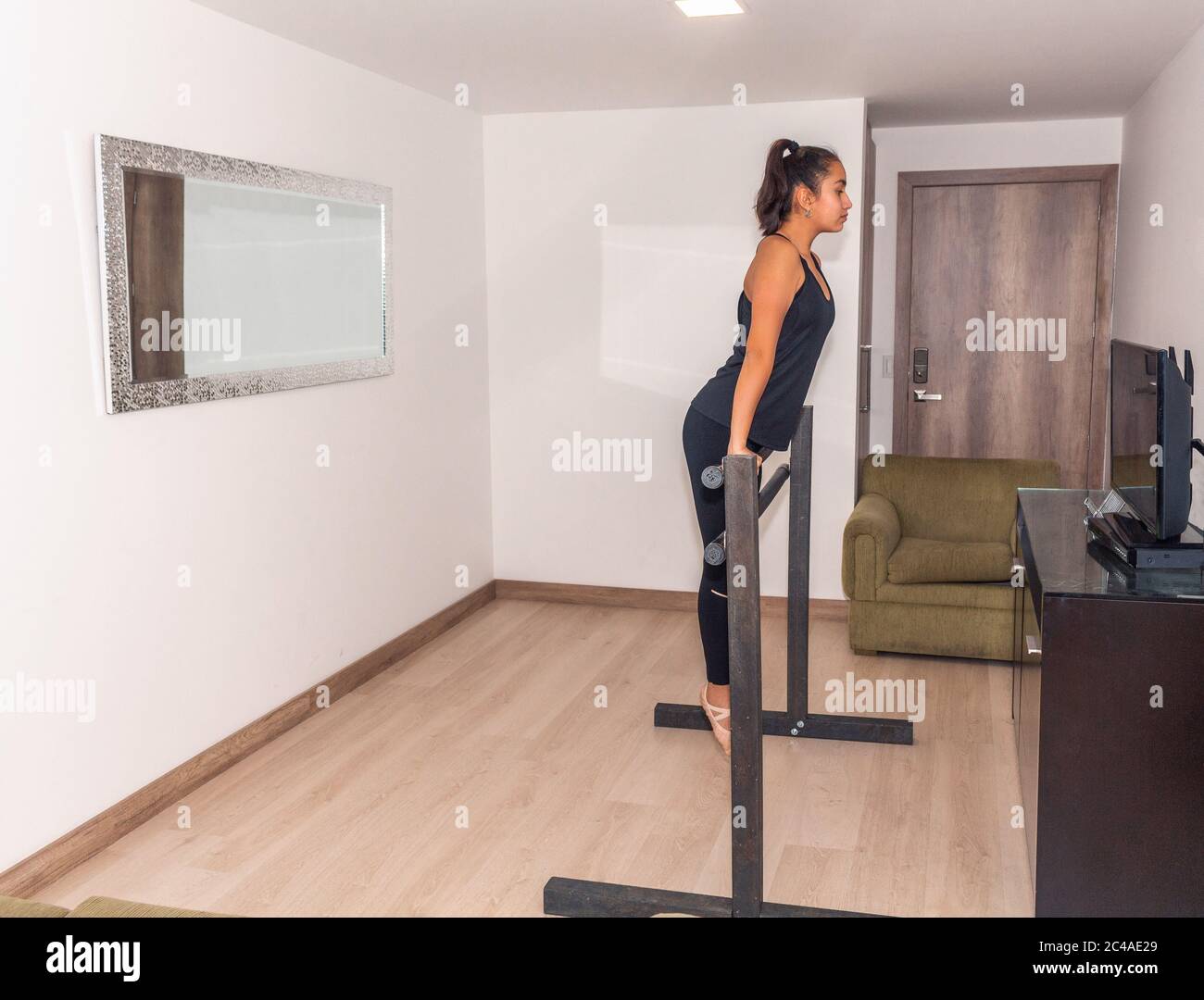 Une adolescente monte dans un bar pour pratiquer la gymnastique dans son salon en regardant un cours sur Internet Banque D'Images