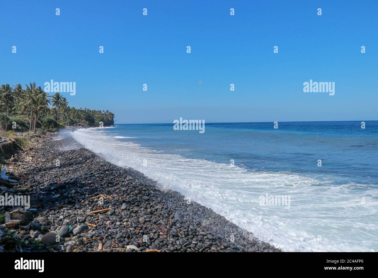 Plage tropicale avec galets noirs. L'île de Bali avec une côte rocheuse.  Plage de sable noir Indonésie Photo Stock - Alamy