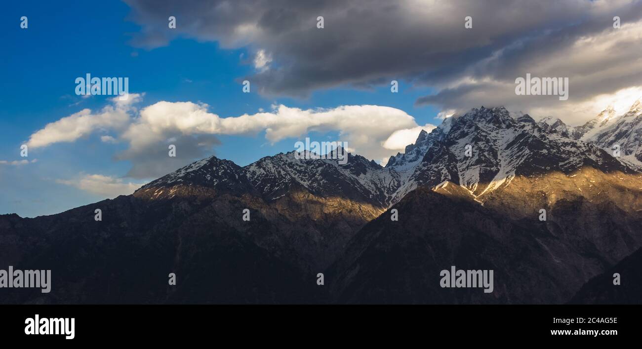 Un petit peu de lumière qui frappe les montagnes de la chaîne de Kinner Kailash avec des nuages planant au-dessus dans le village de Kalpa à Kinnaur, en Inde. Banque D'Images