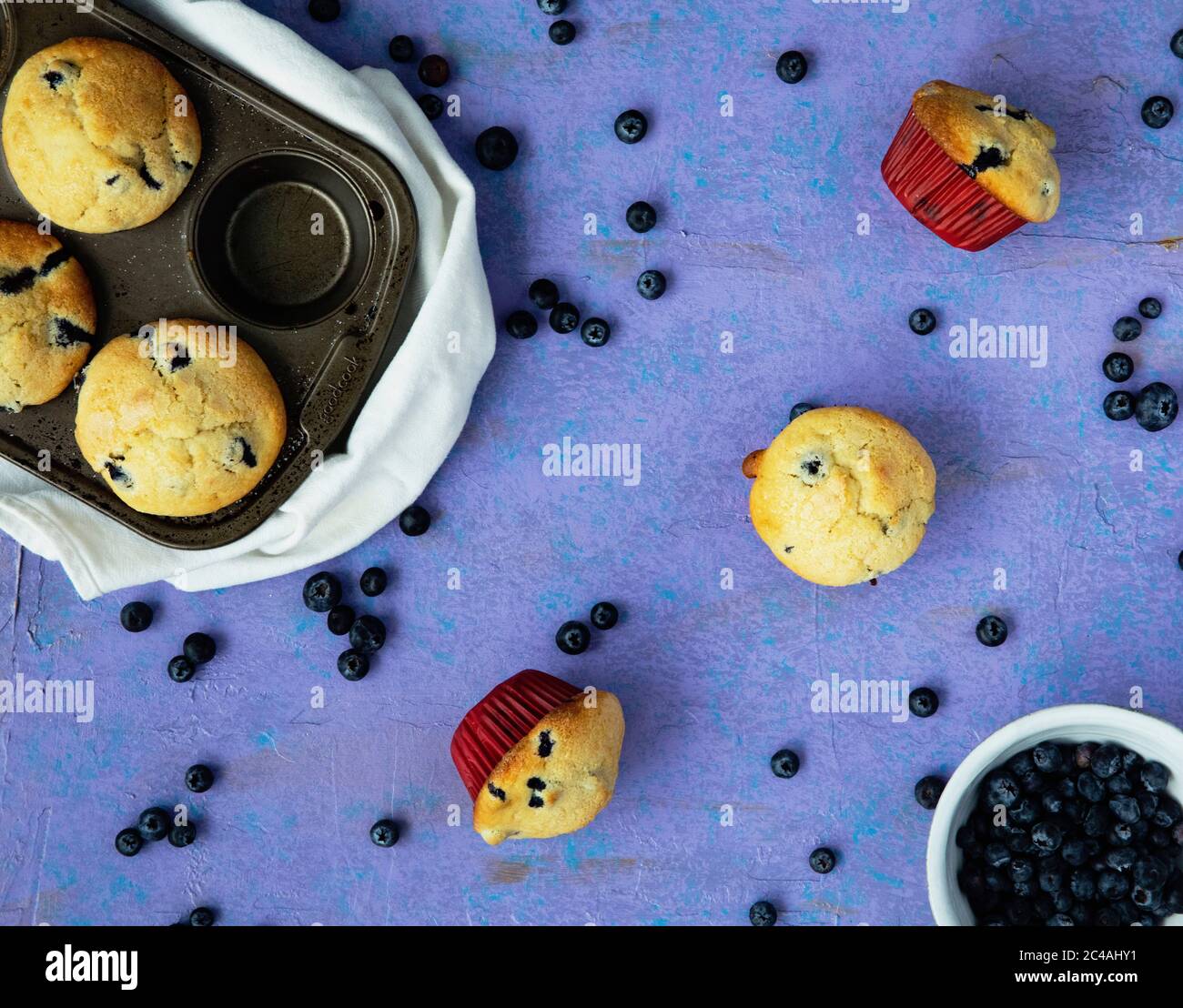 Délicieux muffins aux myrtilles et boîte sur fond violet avec des myrtilles fraîches et biologiques dispersées autour Banque D'Images