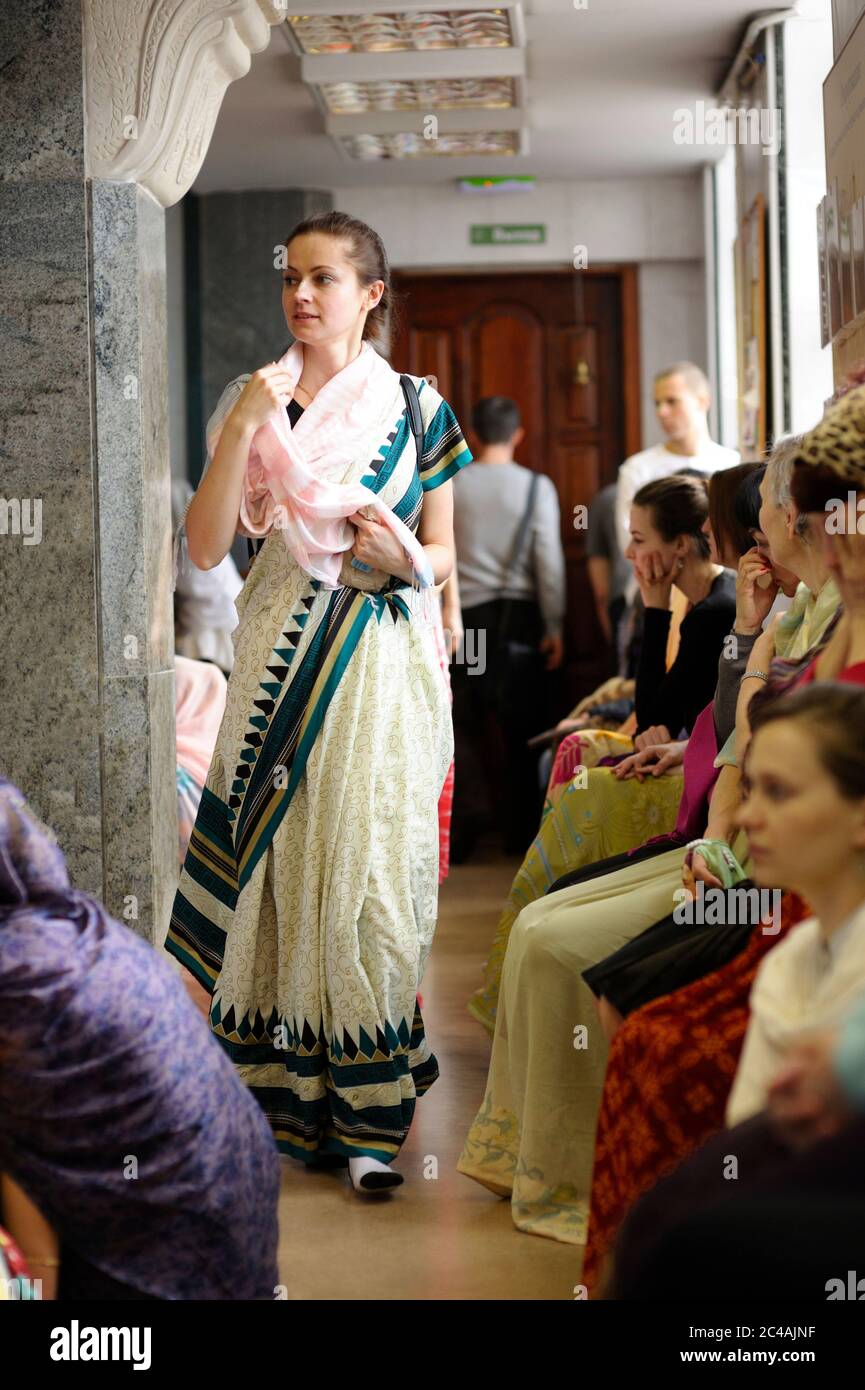 Une jeune femme dans un sari marchant dans un couloir de la Krishna tempe, des gens priant Banque D'Images