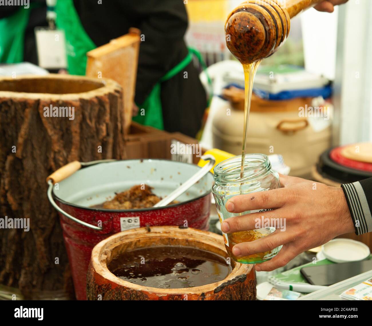 Un fermier remplissant des pots de verre de miel frais Banque D'Images