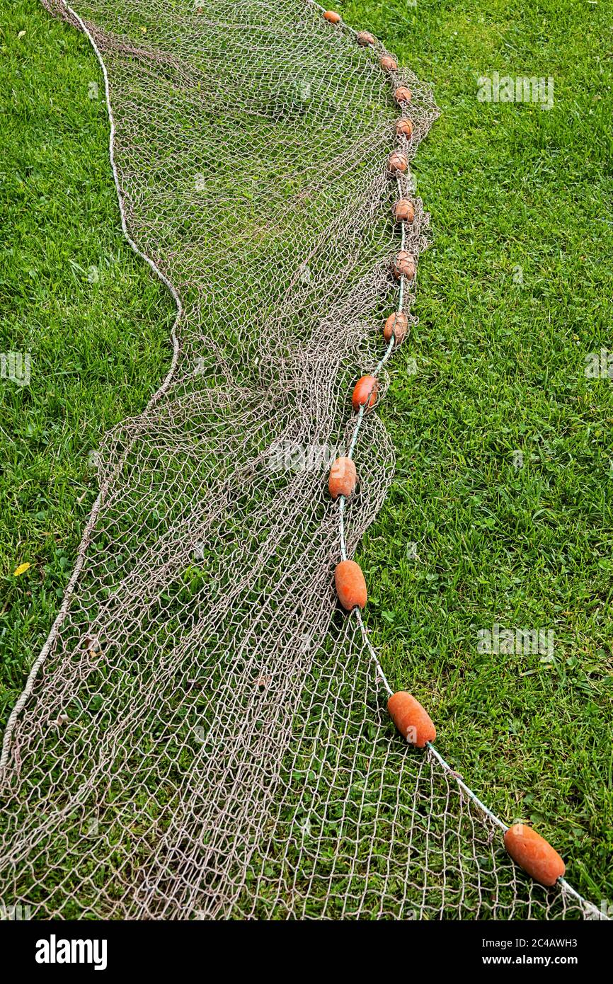 filet de pêche avec flotteurs rouges reposant sur de l'herbe verte Banque D'Images