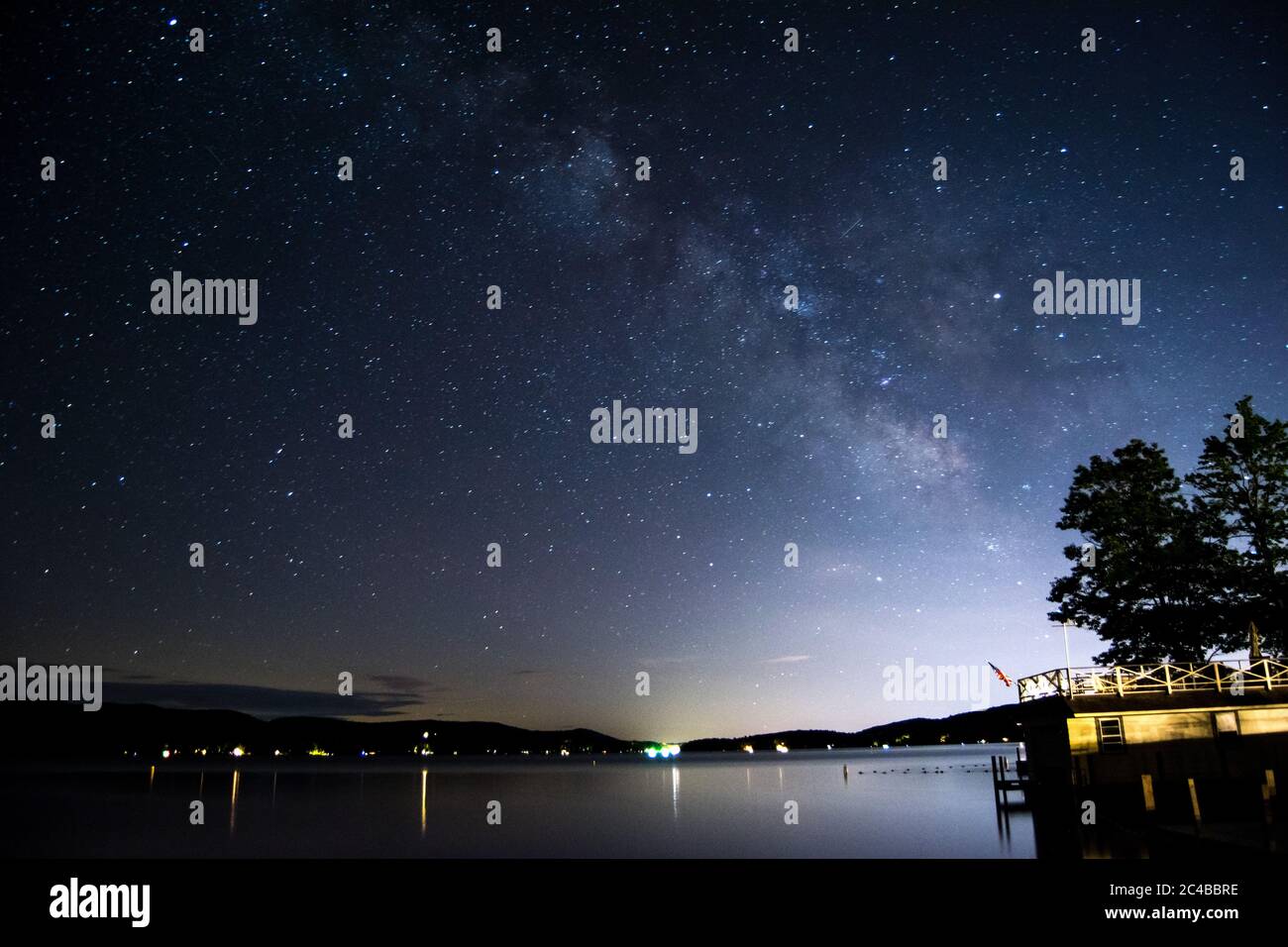 Milky Way Galaxy au-dessus du lac avec pollution lumineuse de la ville entourée par les montagnes Banque D'Images