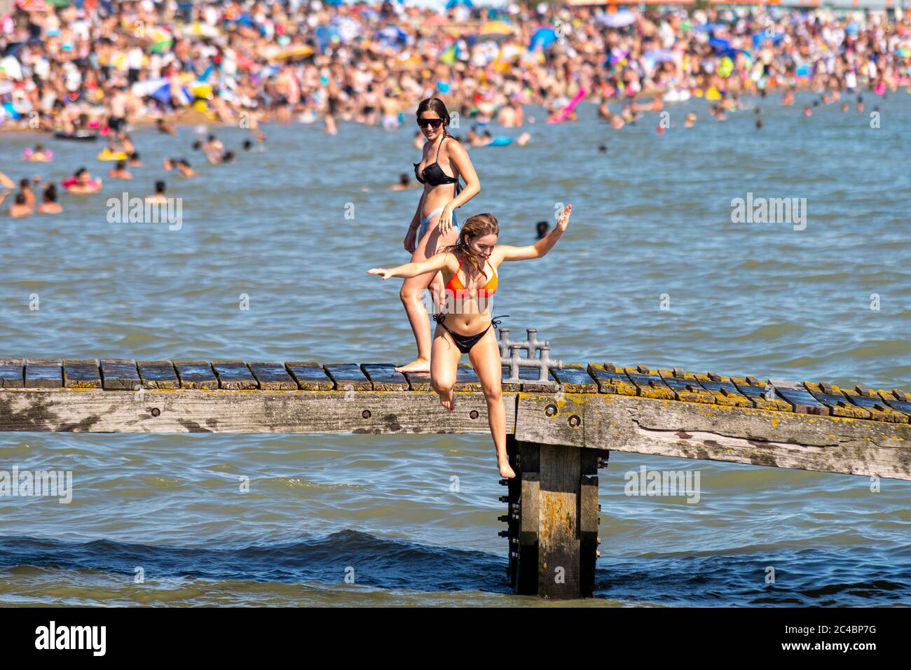Malgré le blocage du coronavirus COVID-19, des foules se sont rendues sur les plages de Southend on Sea, Essex, Royaume-Uni. Jeunes femelles sautant en mer Banque D'Images