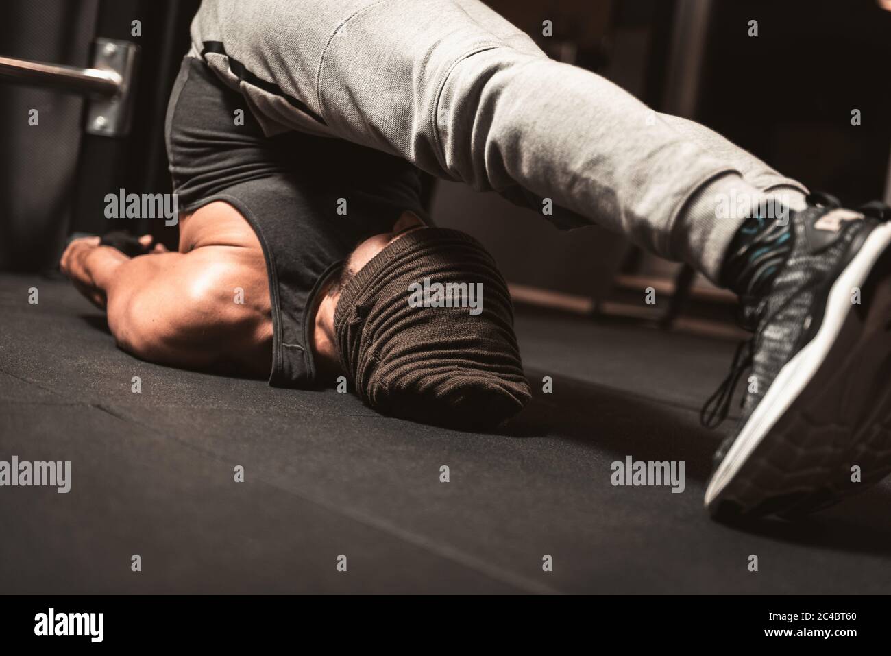 Un sportif dans la salle de gym fait de la relaxation du yoga et des exercices d'arts martiaux. Yoga avantages mentaux. Position de la halasana.(posture de la charrue) Banque D'Images